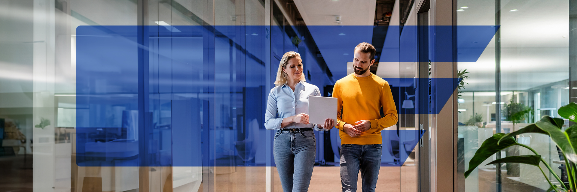 Frau und Mann laufen nebeneinander den Bürogang entlang. Werden Sie Teil unseres Vertrieb-Teams